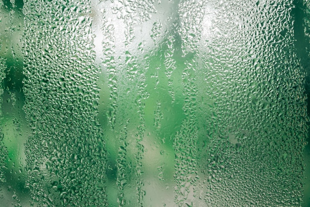 Rain drop on the glass window green Bokeh background environment conceptual, summer rain