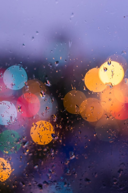 Rain drops in blue glass background City street lights bokeh defocused abstract dusk night city background