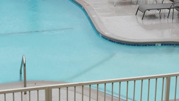 Rain drops falling on water of swimming pool rainy in california motel or hotel