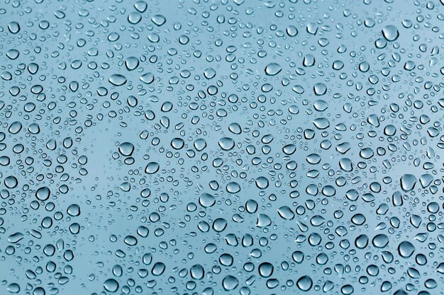 Rain drops on window glasses surface with cloudy background . Natural Pattern of raindrops isolated on cloudy background.