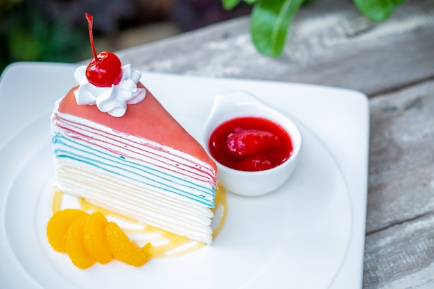 Rainbow crepe cake and a cherry with strawberry sauce 