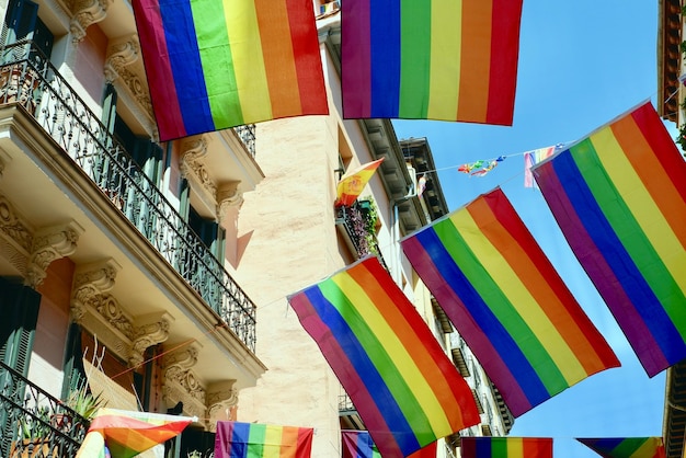 Rainbow festive flags hang between balconies downtown on streets of Chueca district in Madrid Spain