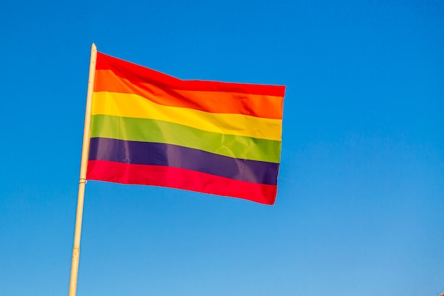 Rainbow flag LGBT movement symbol against blue sky background