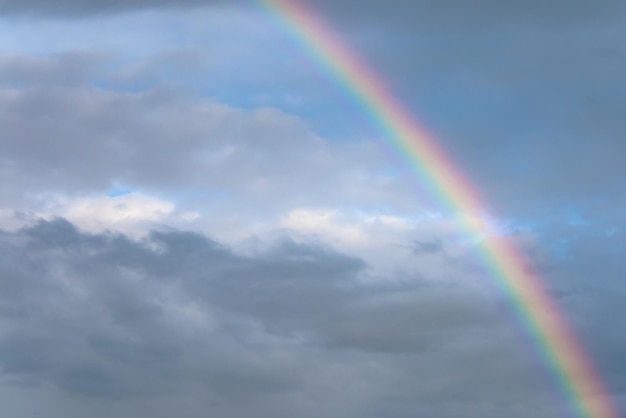 Rainbow formed after rain with clouds and blue sky in the background