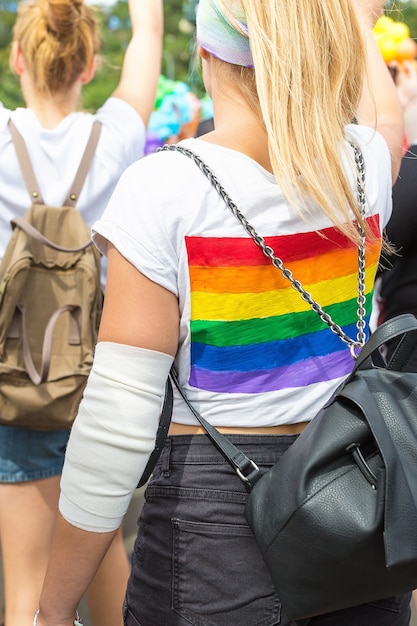 Rainbow LGBT flag on backpack of lady in crowd of people on Prague Pride Parade