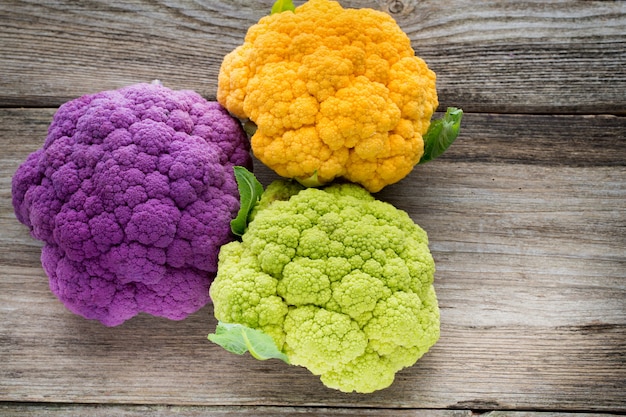 Rainbow of organic cauliflower on the wooden table.