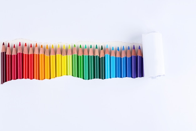 A rainbow of pencils in a strip of torn white paper.