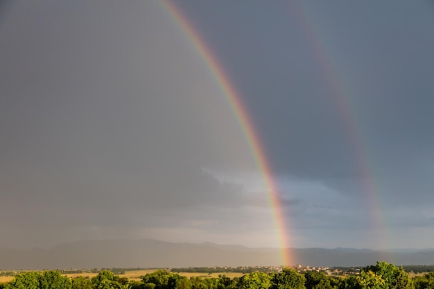 Rainbow over a quaint village and meadows after the rain copy space wallpaper