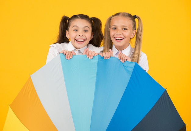 Rainbow umbrella. Colorful life. Schoolgirls happy big umbrella. Fall weather forecast. Place for both of us. Fashion accessory. Girls friends with umbrella. Rainy day. Happy childhood. School time.