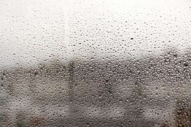 Raindrops on glass on a blurred background rain on the window dripping rain on the window texture photo