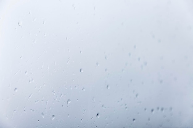 Raindrops on glass Selective focus Sad cloudy weather Grayblue background Space for text