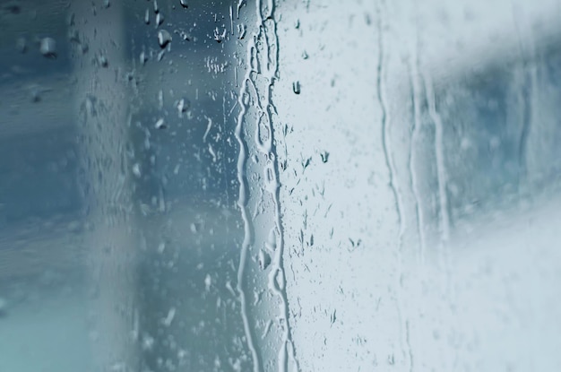 Raindrops on window glass toned blue tilt shift