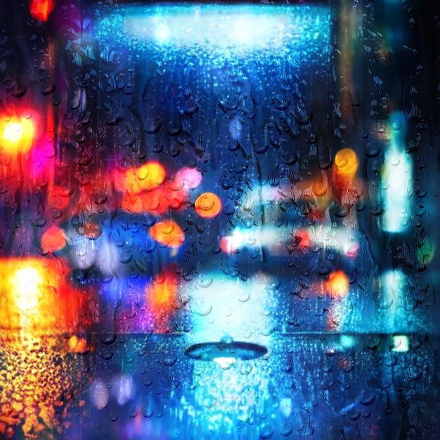 rainy city night car traffic blurred light rain drops on window glass defocus background