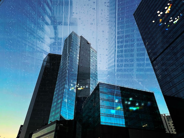 Rainy city view from windows reflection Modern buildings facade windows evening blurred light