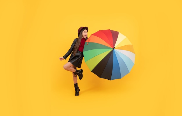 Rainy weather forecast. back to school. fall fashion accessory. happy stylish girl in leather wear. cheerful teen child hold colorful parasol. kid in hat with rainbow umbrella. autumn season.