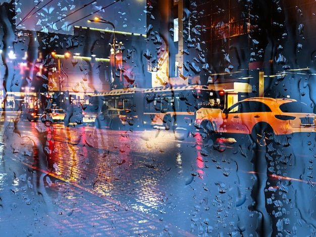 rainy window blurred  evening light car traffic on  stree with rain drops urban weather ,