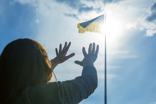 Raised hands to the sky against the background of the flag of Ukraine Prayer for help and