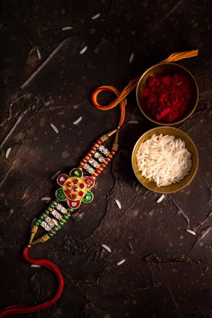 Photo raksha bandhan background with an elegant rakhi, rice grains and kumkum