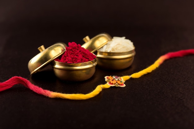 Raksha Bandhan background with an elegant Rakhi, Rice Grains and Kumkum