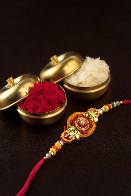 Raksha Bandhan background with an elegant Rakhi, Rice Grains and Kumkum