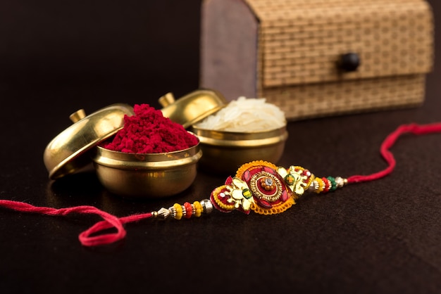 Raksha Bandhan background with an elegant Rakhi, Rice Grains and Kumkum