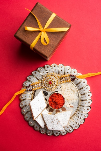 raksha bandhan greeting  rakhi and gift with sweet kaju katli or mithai and rice grains kumkum