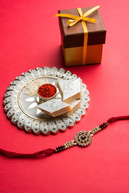 raksha bandhan greeting  rakhi and gift with sweet kaju katli or mithai and rice grains kumkum