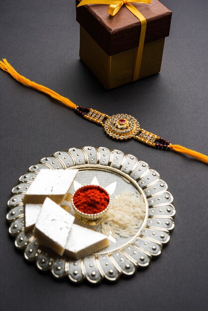 raksha bandhan greeting  rakhi and gift with sweet kaju katli or mithai and rice grains kumkum