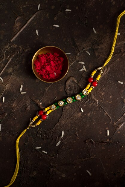 Photo raksha bandhan with an elegant rakhi, rice grains and kumkum. a traditional indian wrist band which is a symbol of love between brothers and sisters.