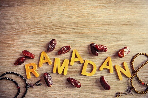 Photo ramadan word with wooden letters rosary and dry dates on table