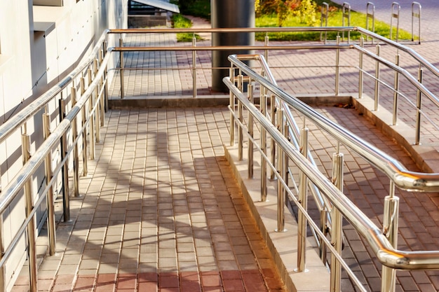 A ramp and metal railings at the entrance to the residential building for the convenience of people with disabilities and the elderly