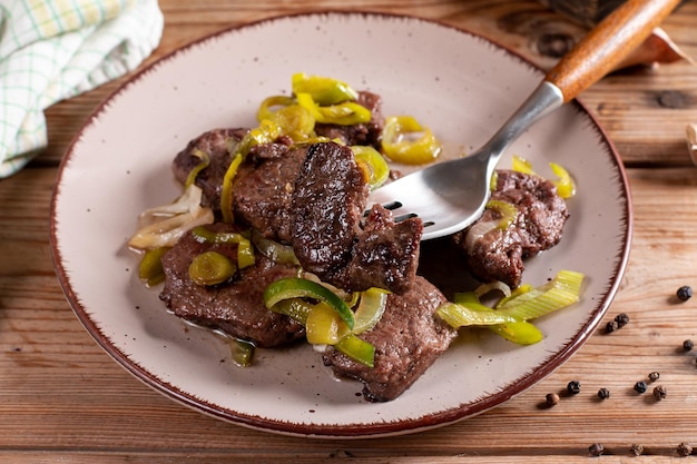 Rare roasted thick juicy beef fillet medallion topped with leek on wooden table