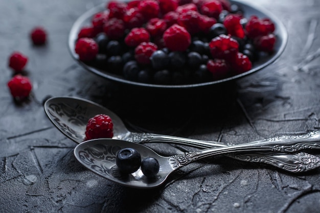 Raspberries and blueberries, on a black background, wild berry