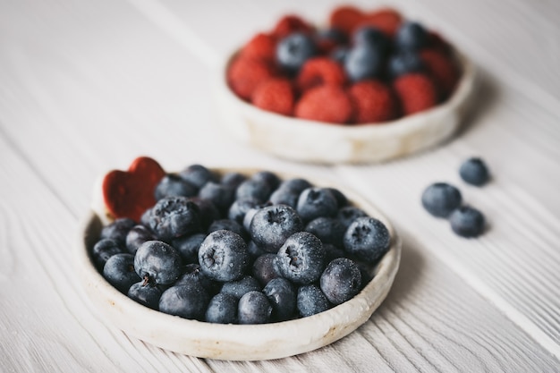 Raspberries and blueberries in small ceramic bowls with red heart decor