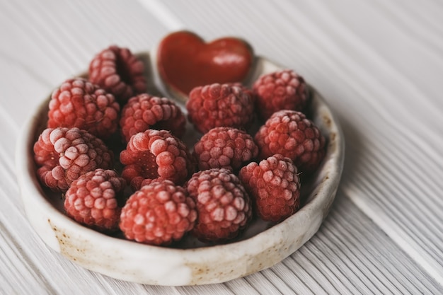 Raspberries  in small ceramic bowl with red heart decor closeup