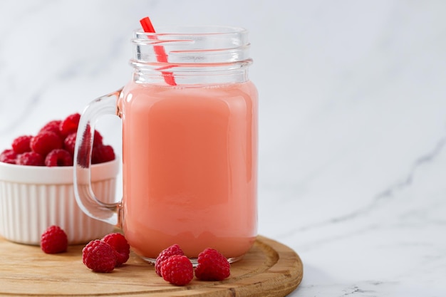 Raspberries smoothie in a glass jar on the breakfast with raspberries copy space