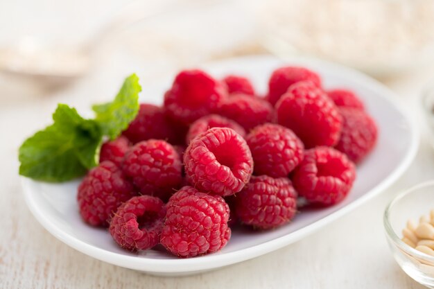 Raspberries on white dish on wooden