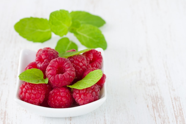 Raspberries with mint in white bowl