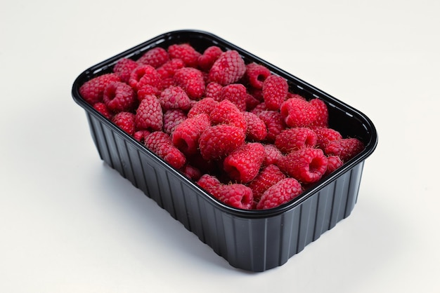 Raspberry in black container isolated on white background