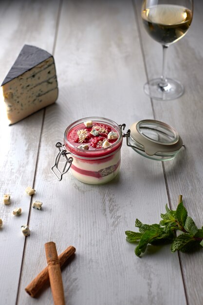 Raspberry - cheese panakota, with a glass of white wine, cheese, mint on a white board