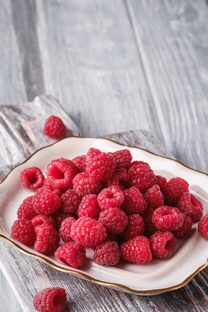 Raspberry fruits in plate on old cutting board