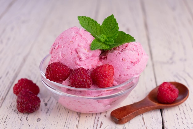 Raspberry ice cream in a transparent glass bowl on a wooden table