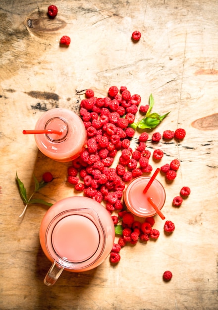 Raspberry juice in the pitcher and glasses. On a wooden table.