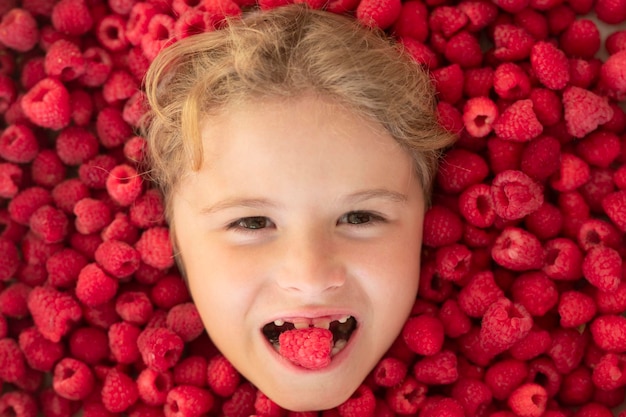 Raspberry in kids mouth kids face in raspberries fruits healthy kids nutrition concept