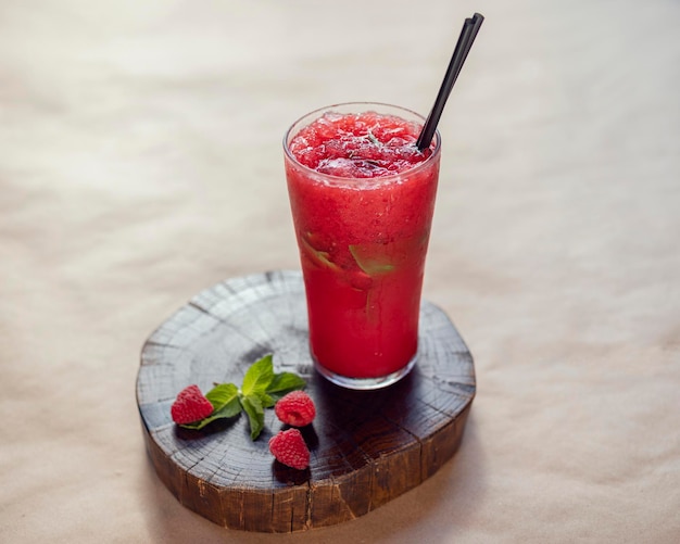 Raspberry lemonade on a wooden stand in a glass beaker