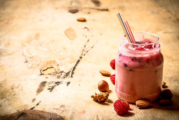 Photo raspberry smoothie with nuts. on wooden background.