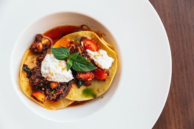 Ravioli with ricotta cheese and tomato served in white plate.