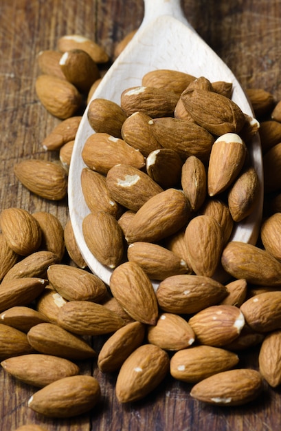 Raw almond on wooden spoon in brown board