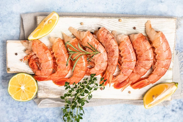 Raw Argentine shrimps on white wooden cutting board with lime herbs and pepper Seafood