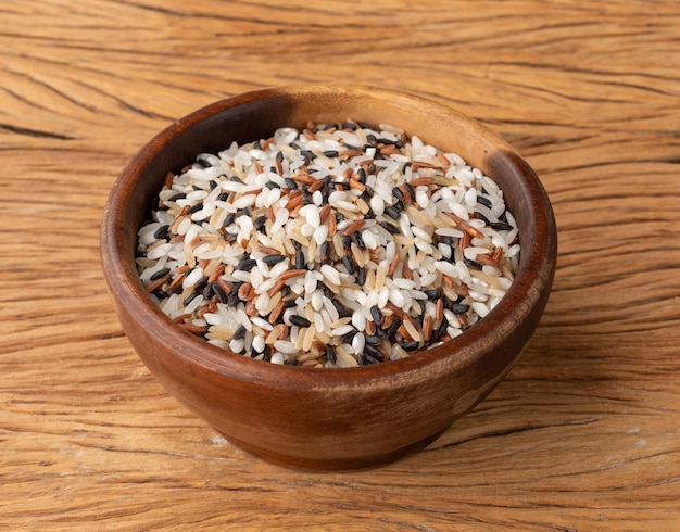 Raw assorted rice in a bowl over wooden table.